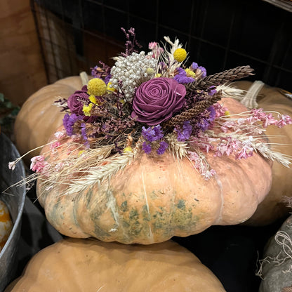 Decorative pumpkin with flowers and herbs on a dark background