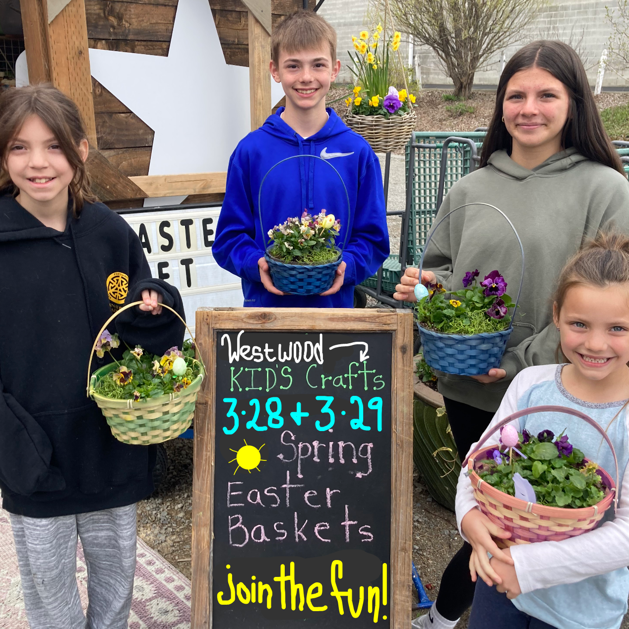 Four children holding flower baskets in front of a sign for kids crafts and Easter events.